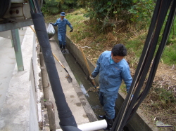 用水路に浮かんだ草や葉を集めている写真