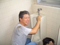 笑顔で小便器を磨いている写真