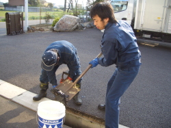側溝のゴミをスコップですくい上げている写真