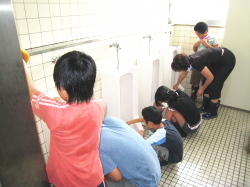 小便器を磨いている小学生の写真